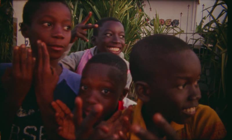 Youths pose outside building showing a number of fingers