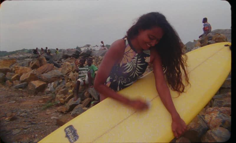 A young woman is cleaning up her surf board outside