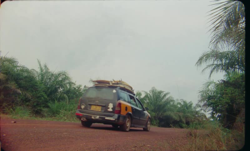 Third world country taxi drives on a dirt road in the tropics caught on vintage film