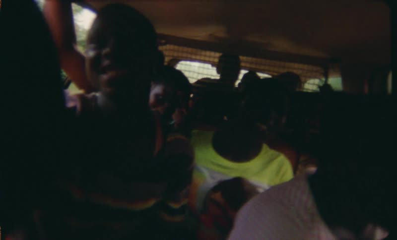 A group of teens and kids in a small bus singing laughing on their way to the beach to go surfing