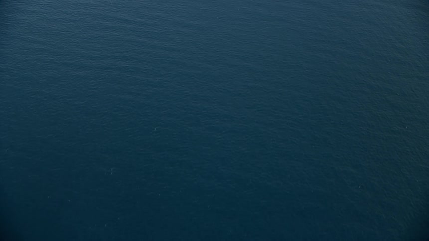 A breathtaking birds eye view of the open waters of the Pacific Ocean off the coast of Southern California during a partly cloudy day in the summer captured by a Shotover F1 camera mounted on an Epic Helium drone