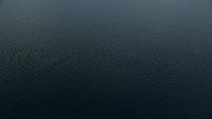 A stunning shot of open water in the Pacific Ocean off the coast of sunny Southern California captured in aerial footage using a Shotover F1 and Epic Helium cameras during the summer months revealing a dark blue body of water with calm waves visible from 