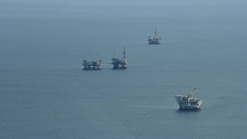 Aerial view of oceanic oil rigs off the coast of Southern California during a partly cloudy day