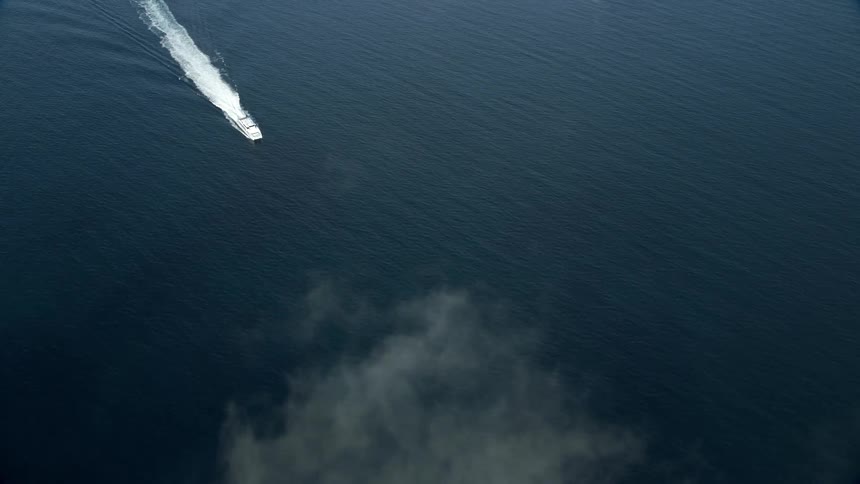 Aerial footage of a ferry approaching the coast of Southern California over open water and partly cloudy skies