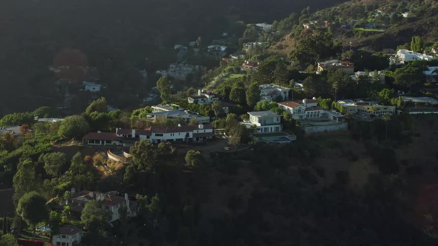 A stunning aerial view of luxurious mansions perched on hilltops in Beverly Hills California bathed in sunlight