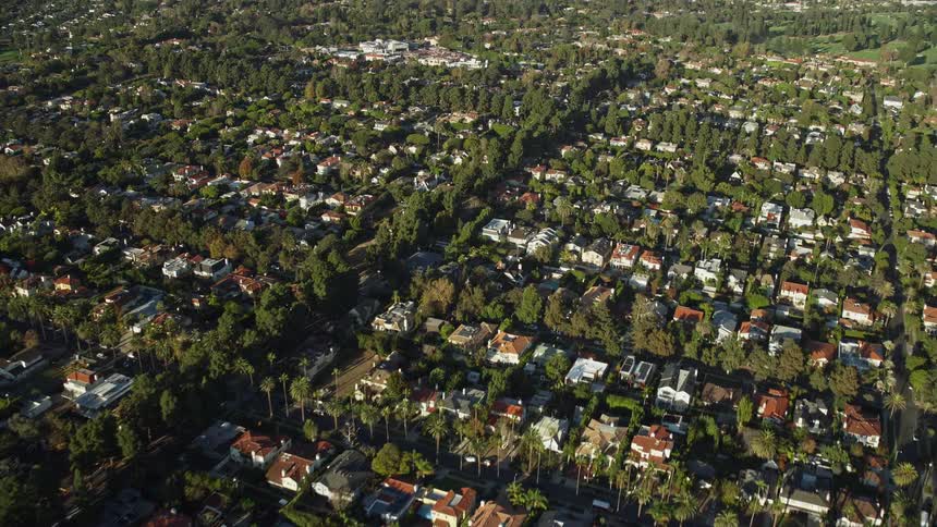 Aerial footage of upscale Santa Monica and Brentwood neighborhoods with mansions and luxury homes shot during a partly cloudy day time with a approach and tilting down shotover F1