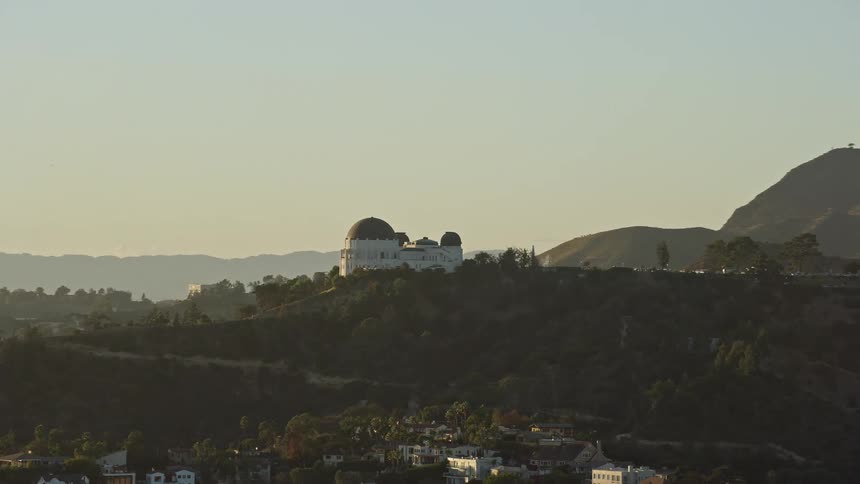 A breathtaking aerial view of the Griffith Observatory orbiting towards the iconic Hollywood Sign in Los Angeles California