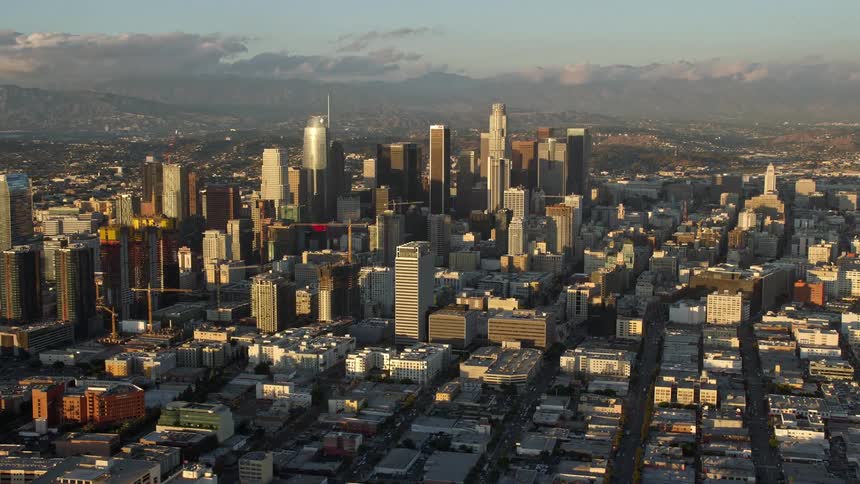 Wide-angle aerial footage of the impressive skyscrapers high-rises and bustling city of Downtown Los Angeles California on a partly cloudy day