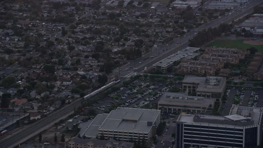 Aerial footage of a Metrolink commuter train passing through neighborhoods at twilight in Burbank CA