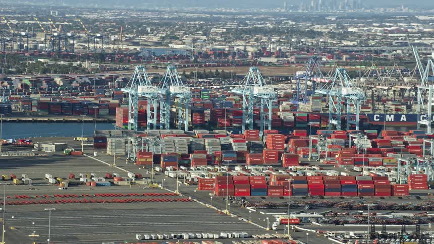 Aerial footage of cargo containers and cranes at the busy Port of Los Angeles California during daytime in partly cloudy skies
