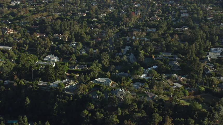 Aerial footage shows upscale mansions in Beverly Hills California during a sunny day