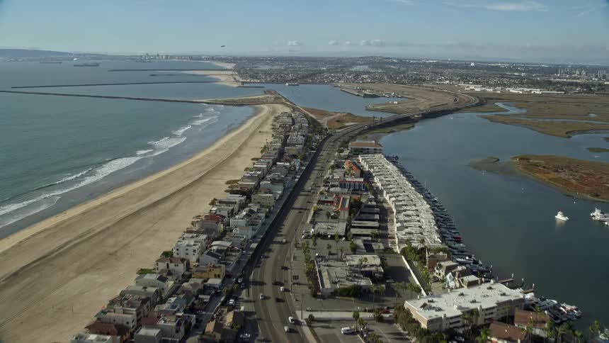 Aerial footage over beachfront homes and highway approaching Seal Beach National Wildlife Refuge in Huntington Beach CA