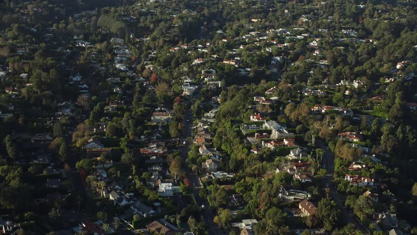 Aerial footage of upscale tree-lined neighborhoods in Brentwood California during a sunny day