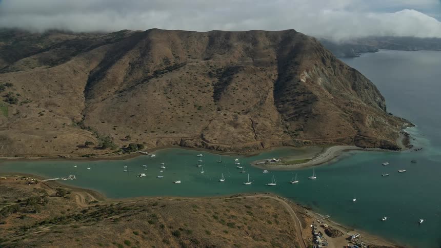 Aerial footage of sailboats in Catalina Harbor Santa Catalina Island as the camera flies over hills towards the harbor