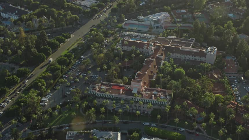 A stunning aerial view of the Beverly Hills Hotel surrounded by lush trees and busy roads on a sunny day in Southern California