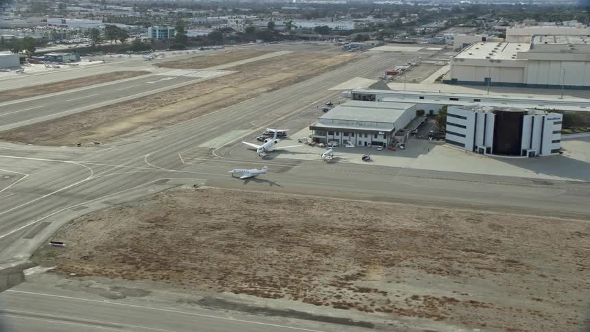 A jet approaches the runway at Long Beach Airport California in this aerial footage during summer daytime