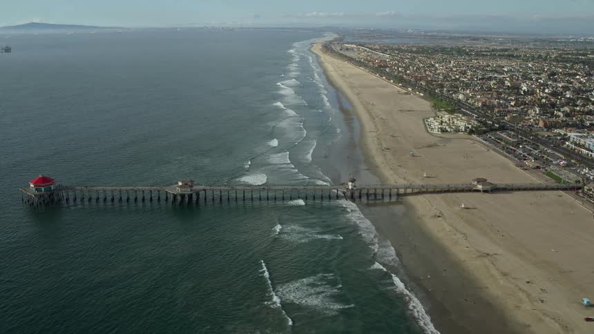 Aerial footage of Huntington Beach Pier and the nearby beach showcasing the scenic seacoast and residential and commercial establishments