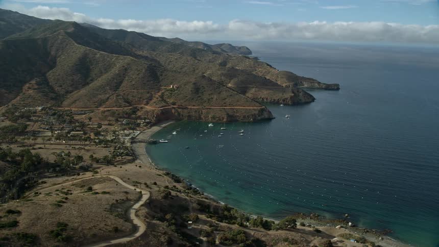 Aerial footage of the small community of Two Harbors on Santa Catalina Island California showcasing the islands seaside residences and harbor docks on a partly cloudy summer day