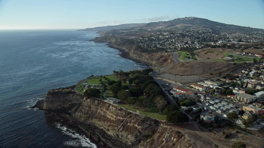 Aerial footage capturing the iconic Point Fermin Lighthouse and homes atop coastal cliffs in San Pedro California showcasing the stunning Southern Californian shoreline during a sunny summer day