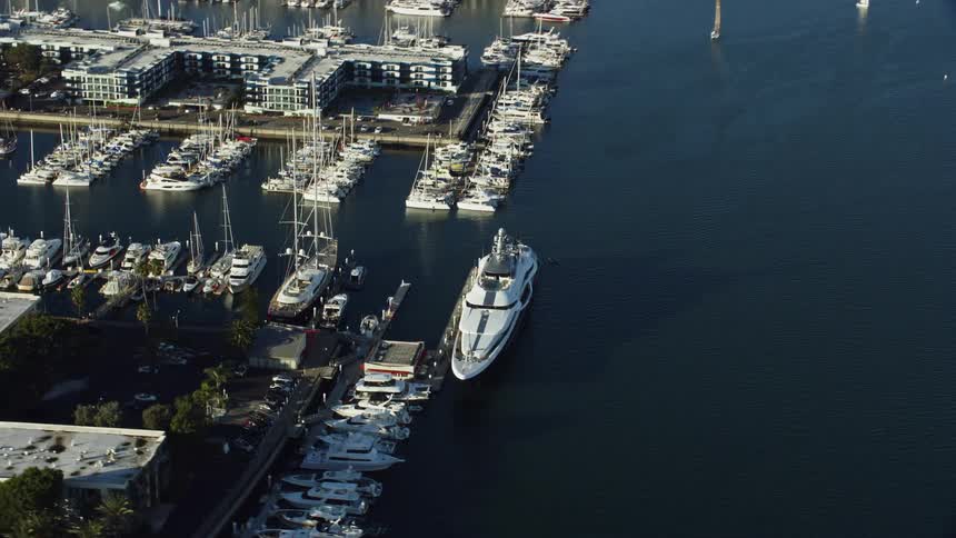Aerial footage of a large yacht docked in Marina del Rey CA on a partly cloudy day