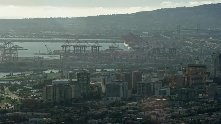 Aerial view of cargo cranes at the port and downtown office buildings in Long Beach California on a hazy day - shot during daytime with an Epic Helium camera