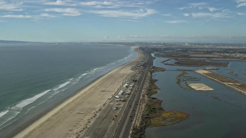 Aerial view of Highway 1 and Bolsa Chica Basin State Marine Conservation Area in Huntington Beach California with light traffic and partly cloudy skies