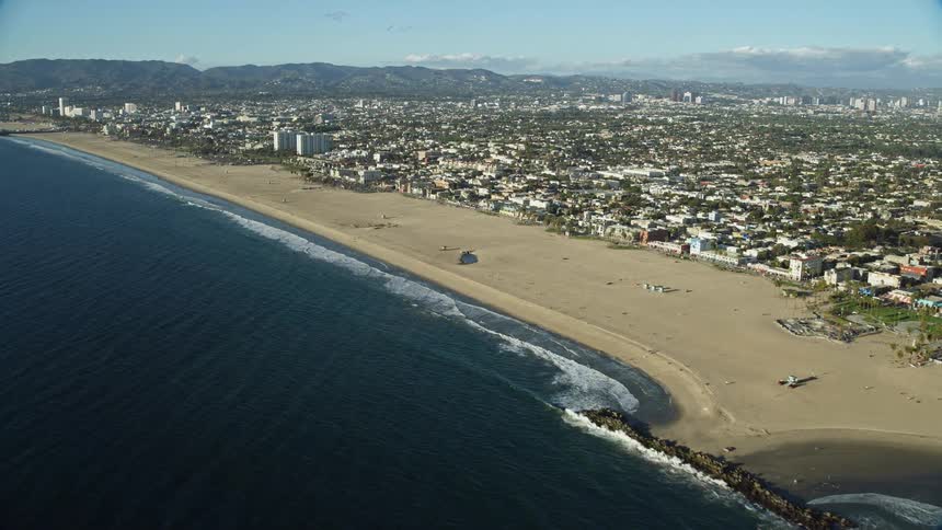 Aerial footage showcasing the iconic Muscle Beach area and Windward Plaza at Venice Beach in Southern California with a view of the shoreline and nearby residential neighborhoods