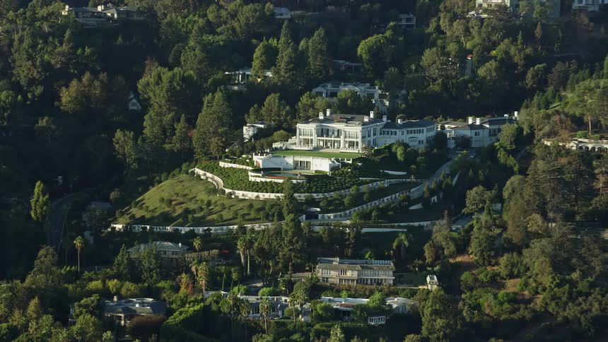 An epic aerial view of a luxurious hillside mansion in sunny Beverly Hills California