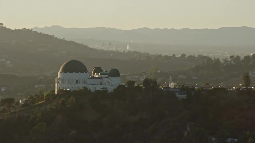  aerial footage of Griffith Observatory & Hollywood Sign in the background; Approaching the iconic structure during daytime revealing partly cloudy skies in Los Angeles California