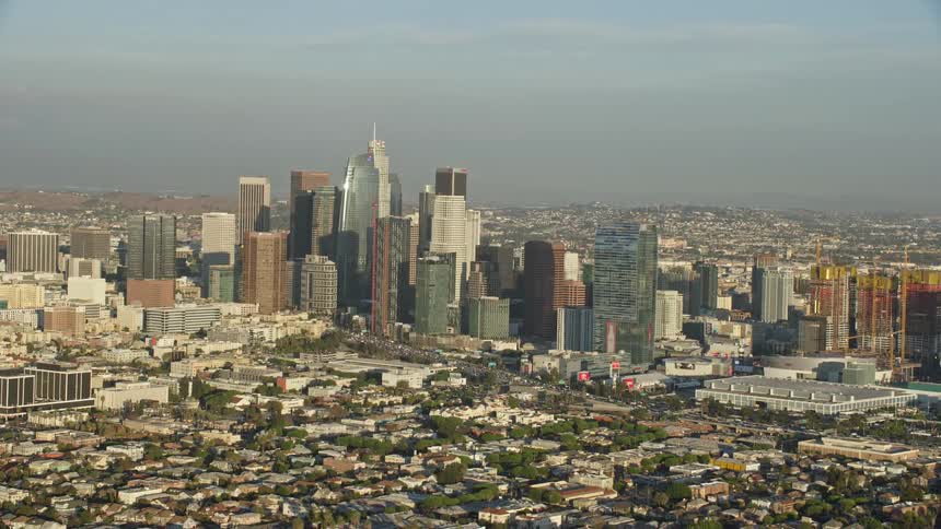 This is a aerial footage of the towering skyscrapers in Downtown Los Angeles during a partly cloudy day