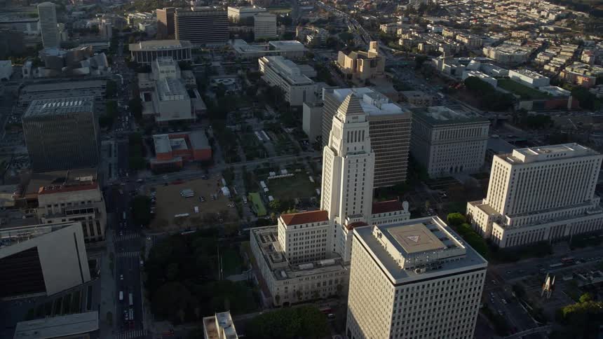 Aerial footage approaching and orbiting Los Angeles City Hall in Downtown LA on a partly cloudy day