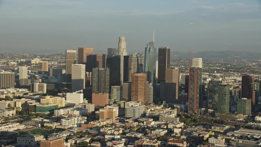  aerial footage showcasing the towering skyline of Downtown Los Angeles shot during a partly cloudy day from a side view perspective