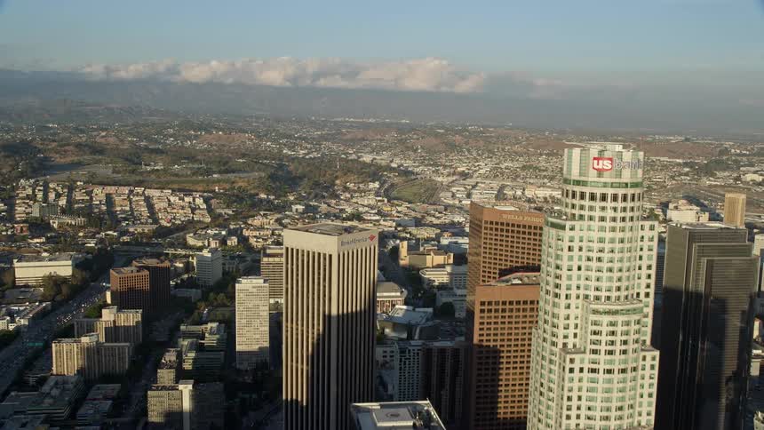 Flying between the Wilshire Grand Center and the Aon Center to approach the US Bank Tower in Downtown Los Angeles on a partly cloudy day showcasing the citys high rises and skyscrapers