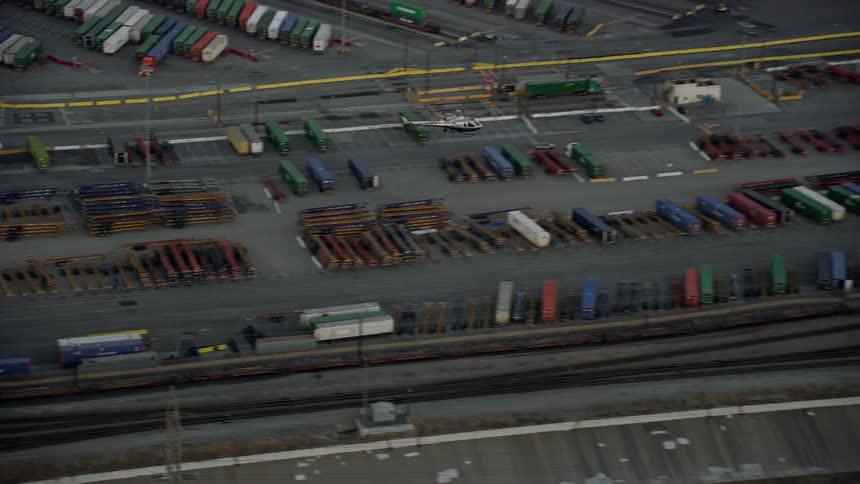 An LAPD helicopter flies over shipping containers in Downtown Los Angeles at twilight in aerial stock footage