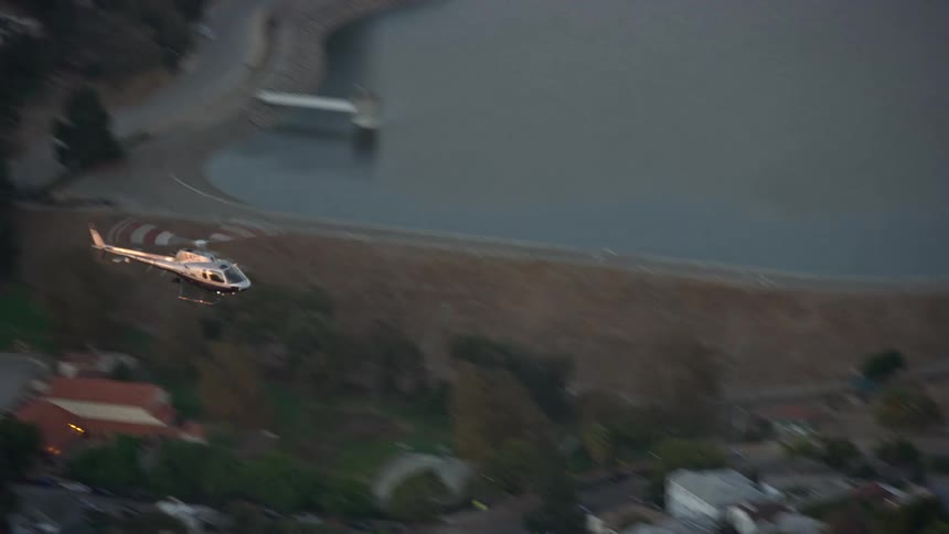 A LAPD helicopter flies over Silver Lake during twilight in Los Angeles CA captured in aerial footage