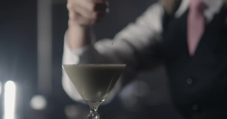 A bartender garnishing an alcoholic beverage
