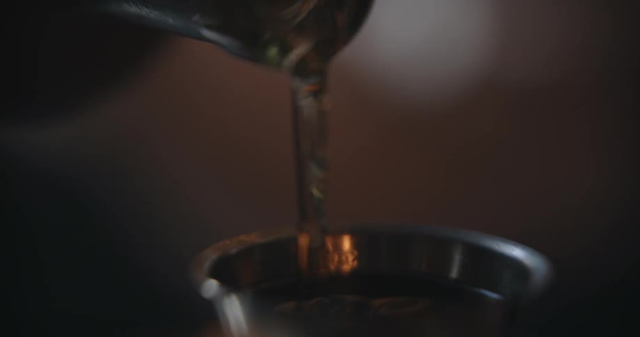Close up of liquid being poured int a metal measuring cup