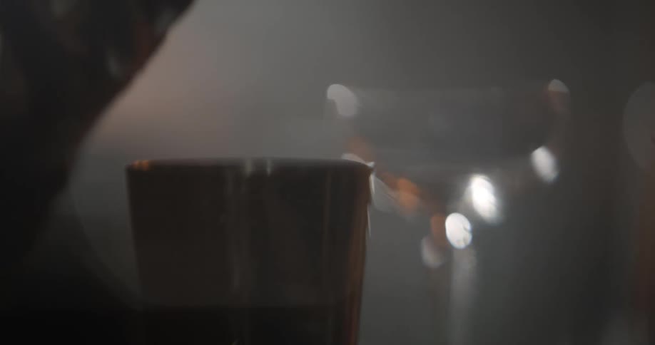 Part abstract blurred shot of liquid pouring into a cocktail shaker from a measuring cup