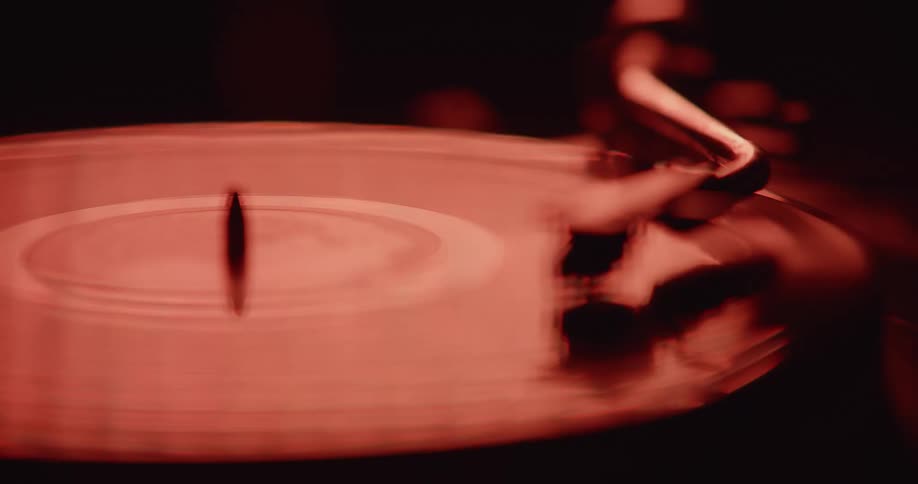 Close up of vinyl on a record deck with flashing red and white ambient light