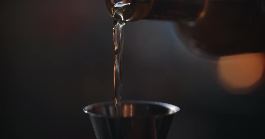 A liquid beverage is being poured into a measuring cup