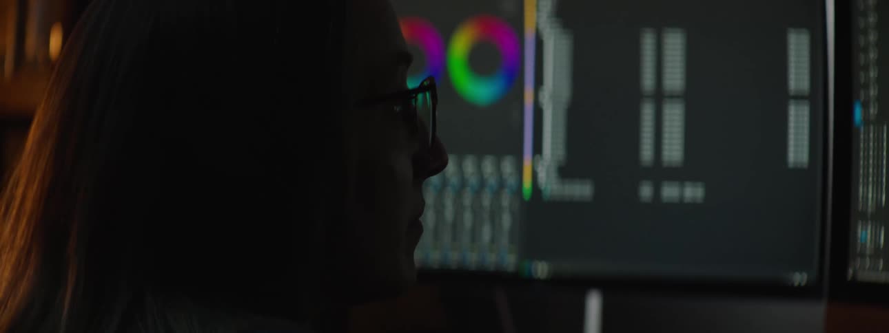 Woman with brown hair and glasses works on computer