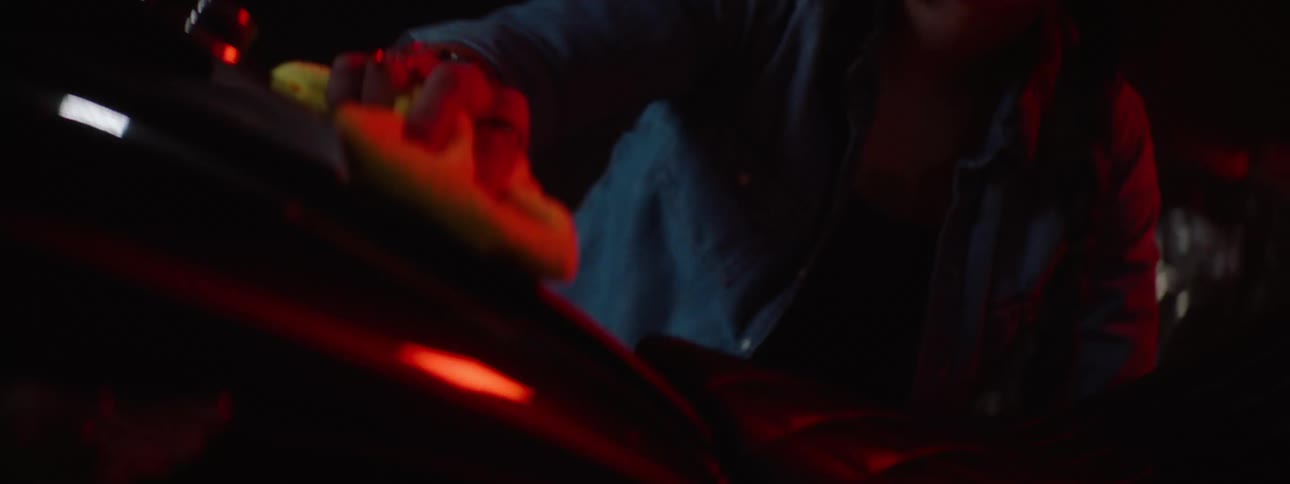 A woman using a rag to wipe down a black shiny metal