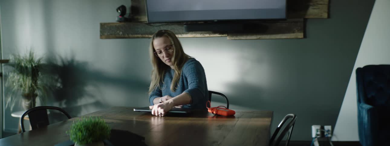A woman sits down with her laptop at her kitchen table