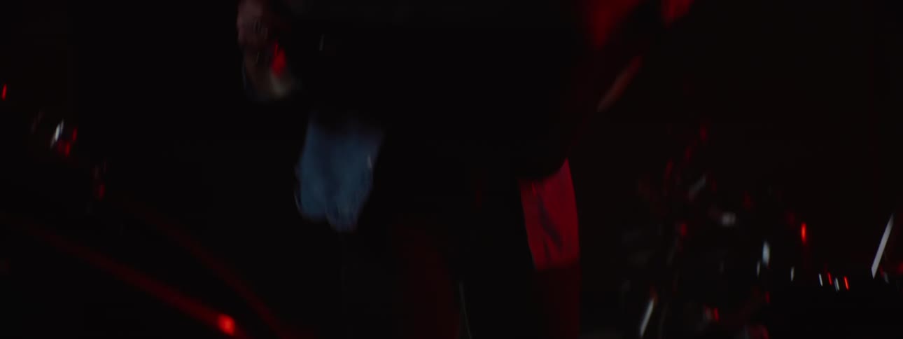 Woman lifts seat off motorcycle in area lit by red lighting and examines the seat