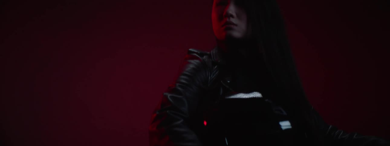 A close up of a woman wearing a black leather suit holding a helmet standing next to a motorcycle