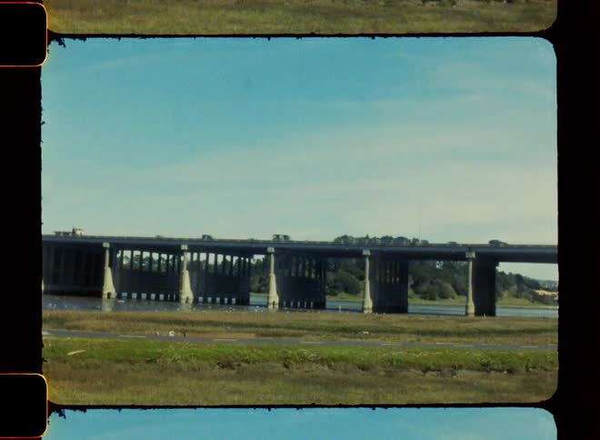 Vehicles drive down a bridge over a river