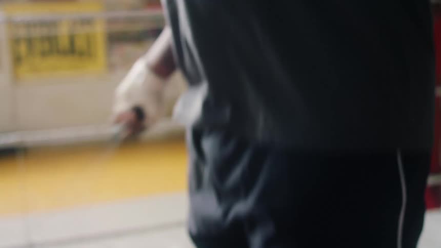 A man with his hands wrapped is jumping rope on a wooden floor in a room