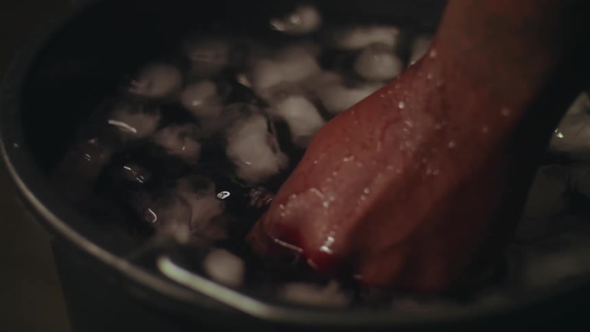 A person dunks their hand in the ice water
