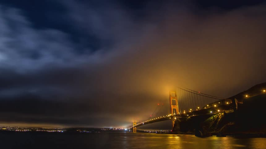 Dark storm clouds move over a bridge and ocean