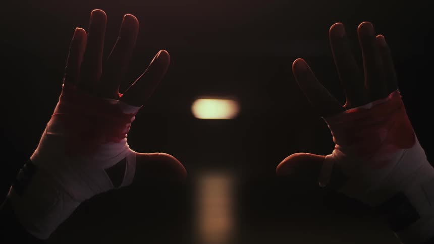 A close up of a persons bloody knuckles wrapped in white hand wraps